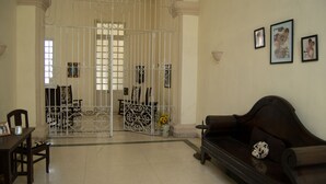 A living room with a sofa, a dining table with chairs, and a decorative vase with flowers. - Hostal Sagrada Familia (Matanzas)