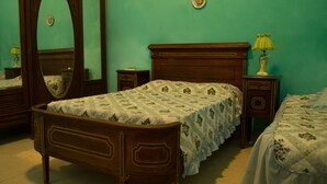 A bedroom with a wooden bed, a nightstand, a lamp, and a mirror. - Hostal Sagrada Familia (Matanzas)