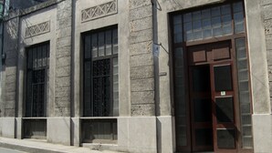 A building facade with three large windows, each with metal bars, and a central entrance with a brown door. - Hostal Sagrada Familia (Matanzas)