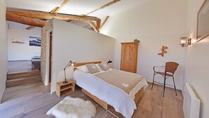 Quarto com cama de madeira, mesa de cabeceira, cadeira, guarda-roupa e um pequeno tapete.