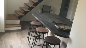Cozinha moderna com bancada escura, degraus de madeira e banquetas.