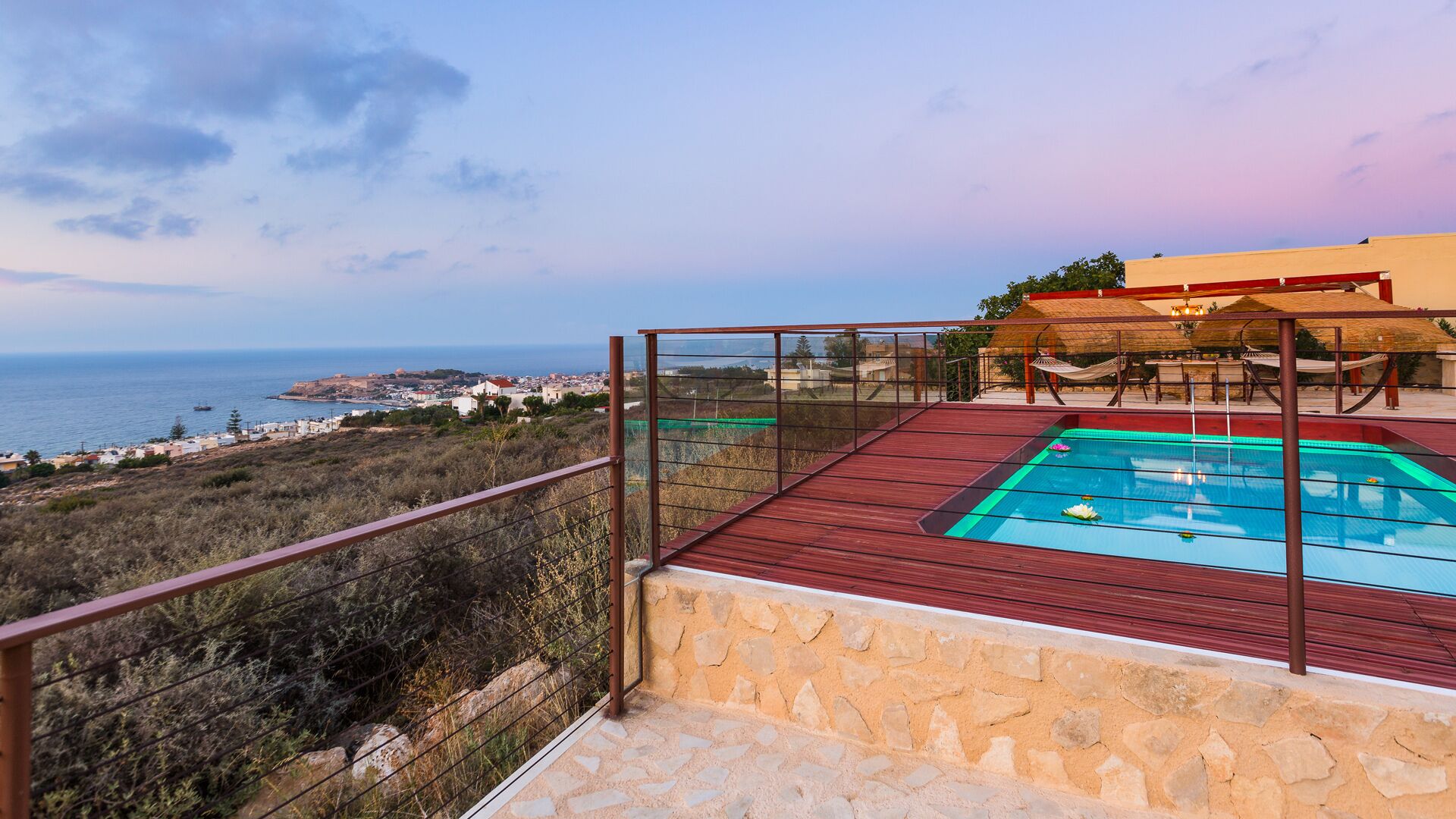 Piscina en la azotea con vista despejada al mar y un pueblo lejano.
