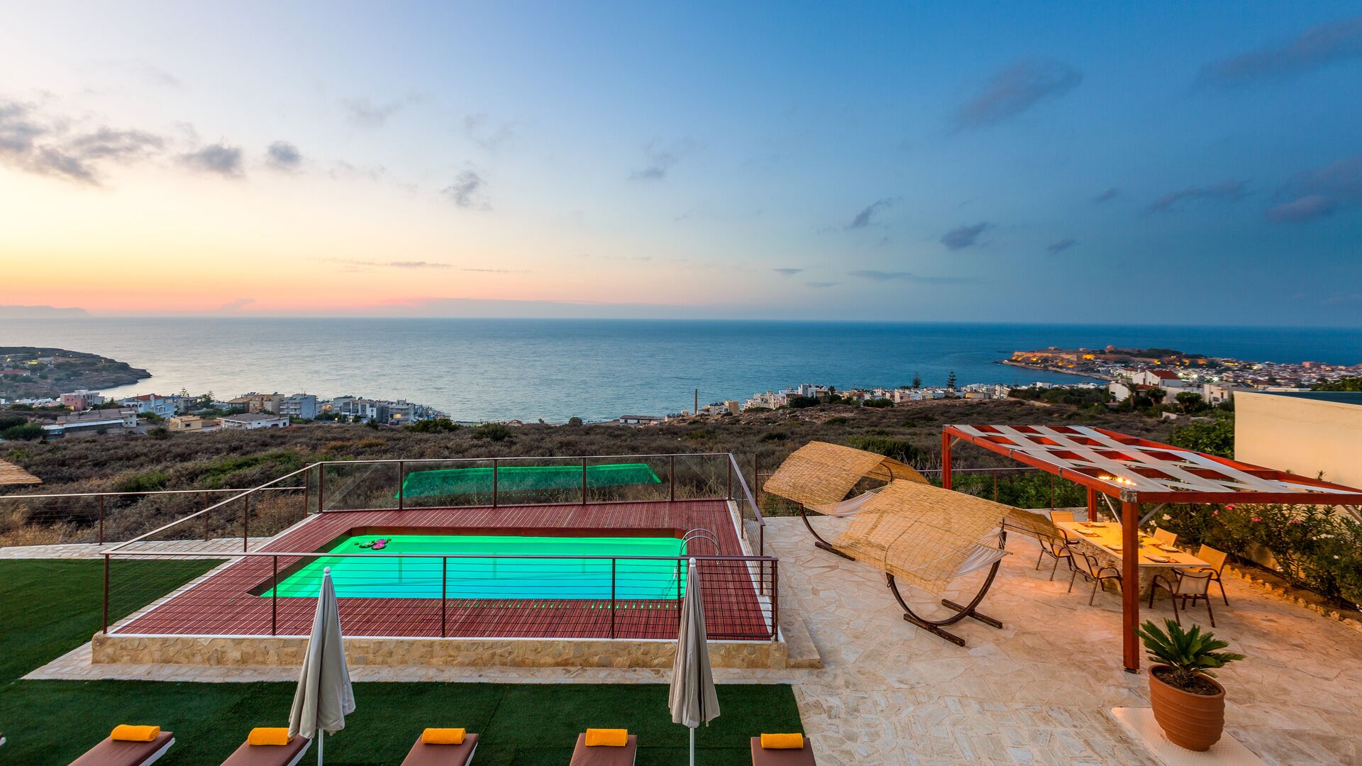 Area piscina sul tetto con vista sul mare, campo da tennis e posti a sedere all'aperto.