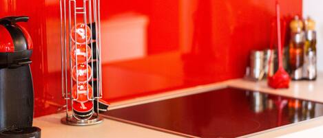 A kitchen with a red backsplash, a coffee maker, and a glass carafe with a red liquid.