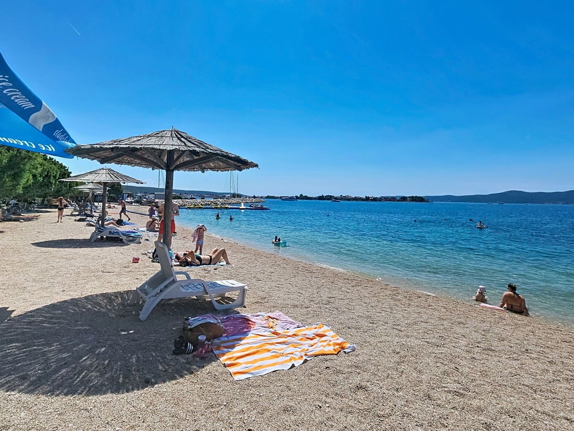 Una platja amb ombrel·les, gandules i gent banyant-se.