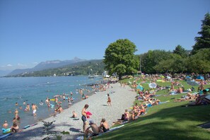 A crowded beach with people sunbathing and swimming, surrounded by trees and mountains in the background. - 2-room apartment, 5 minutes from the gondola, parking, Wi-Fi. (Thollon-Les-Mémises)