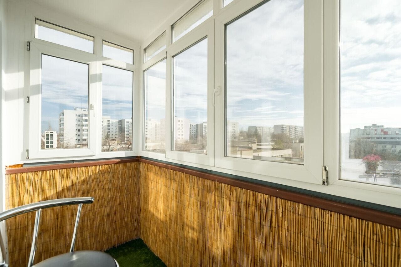 Une pièce dotée de grandes fenêtres, d’un mur en bois et d’une chaise.