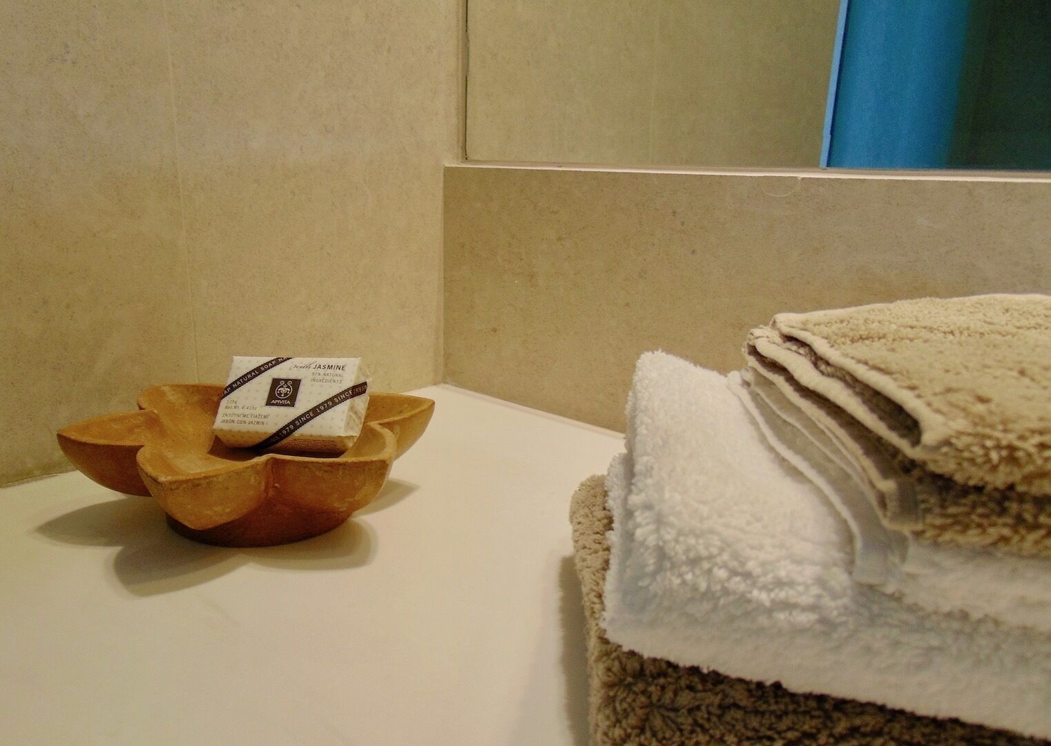 Un bagno con una ciotola di legno contenente una saponetta e una pila di asciugamani.