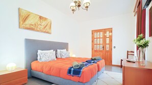 A bedroom with a bed, nightstands, a dresser, a door, and a painting on the wall.