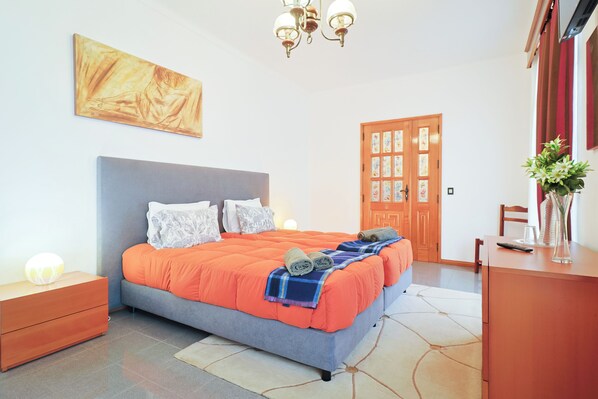 Une chambre à coucher avec un lit, des tables de chevet, une commode, une porte et un tableau au mur.