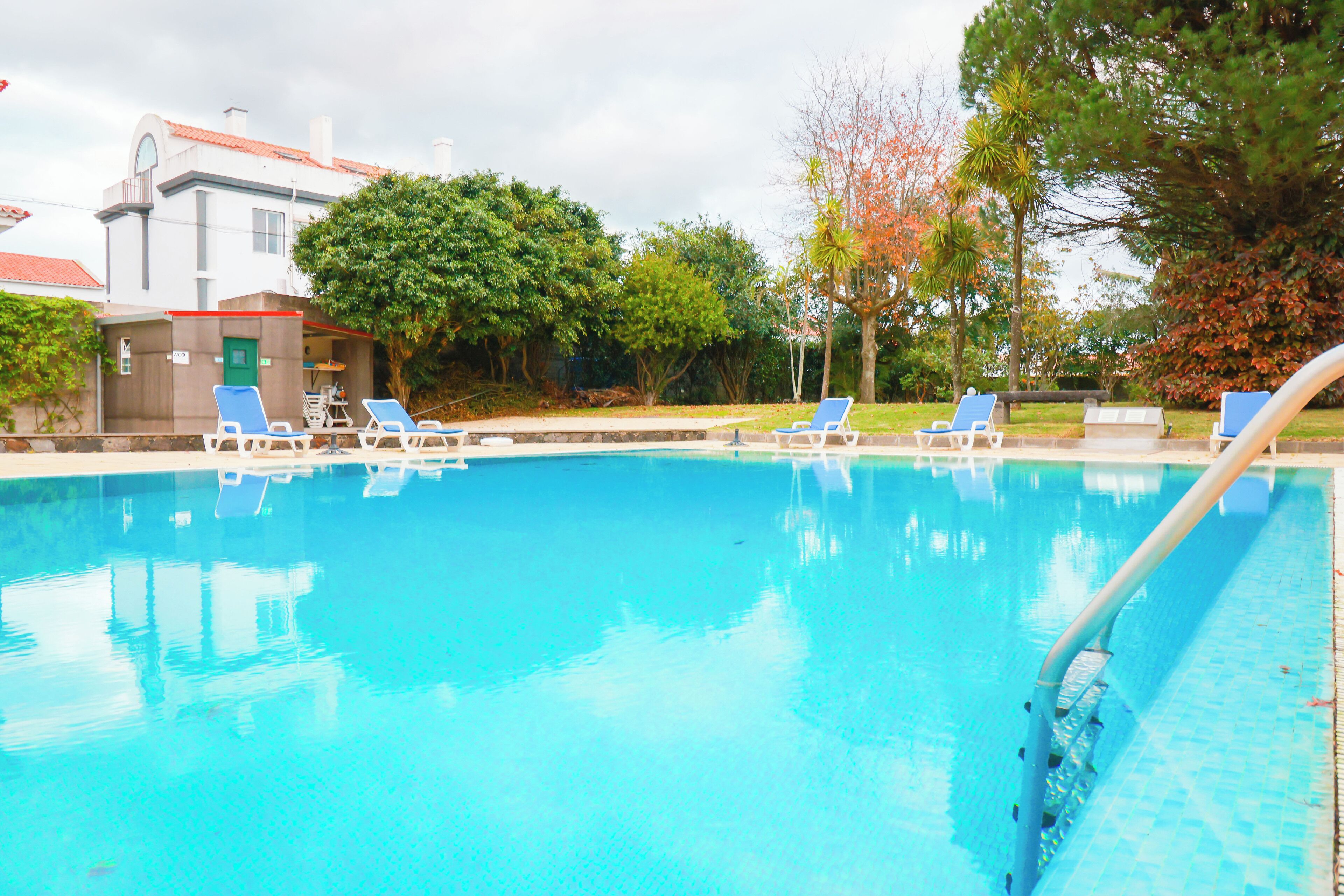 A swimming pool with blue chairs and a building in the background.
