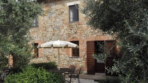 Edificio de piedra con un patio que tiene una mesa y sillas bajo una sombrilla.