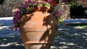 Una maceta de terracota con flores frente a un edificio de piedra con tejado de tejas.