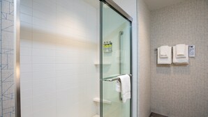 A modern bathroom with a glass-enclosed shower, white tiled walls, and a wooden floor. - Holiday Inn Express Lethbridge Southeast by IHG (Lethbridge)
