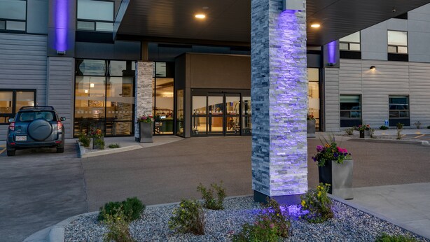A modern building with a stone pillar, a car parked in front, and a well-lit entrance. - Holiday Inn Express Lethbridge Southeast by IHG (Lethbridge)
