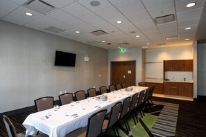 A conference room with a long table, chairs, a flat-screen TV, and a kitchenette area. - Holiday Inn Express Lethbridge Southeast by IHG (Lethbridge)
