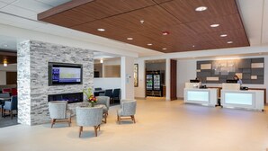 A modern hotel lobby with a stone accent wall, a flat-screen TV, seating area, and a reception desk. - Holiday Inn Express Lethbridge Southeast by IHG (Lethbridge)