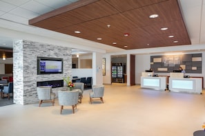 A modern hotel lobby with a stone accent wall, a flat-screen TV, seating area, and a reception desk. - Holiday Inn Express Lethbridge Southeast by IHG (Lethbridge)