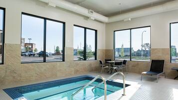 A hotel indoor pool with clear views of the parking lot and buildings outside.