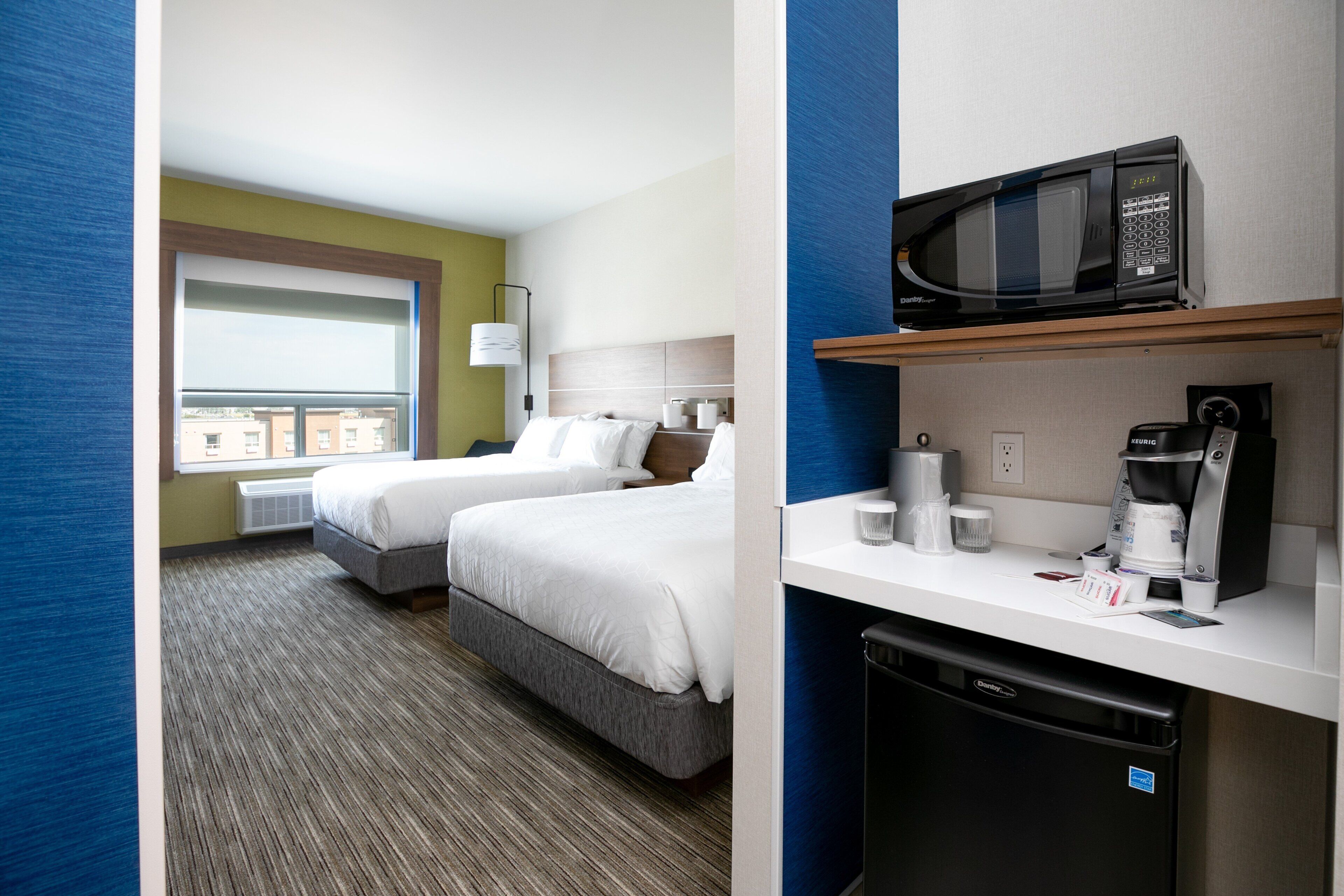 Une chambre d’hôtel avec deux lits, une fenêtre, un four à micro-ondes, une machine à café et un lave-vaisselle.