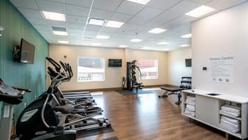 Un gimnasio con cintas de correr, máquinas de pesas y mancuernas.