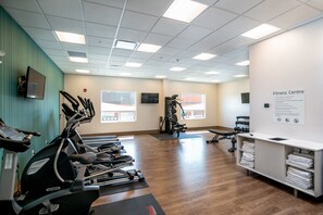 Un gimnasio con cintas de correr, máquinas de pesas y mancuernas.