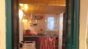 Et lille køkken med træskabe, et spisebord og en grøn dør.