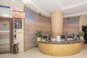 Ein Hotel-Rezeptionsbereich mit Marmor-Theke, einer großen Säule und einem Wandgemälde.