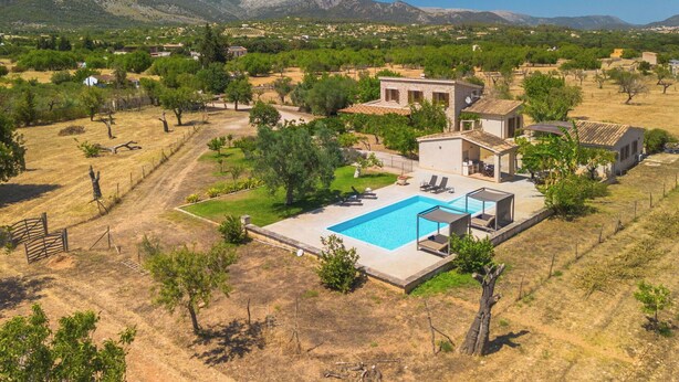 Una villa moderna con piscina, rodeada por un paisaje árido y montañas al lejano.