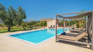 Una piscina con sillas de descanso, una pérgola y vistas a las montañas.