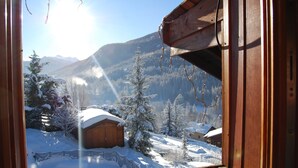 Eine Holzhütte mit Blick auf schneebedeckte Berge und Bäume.