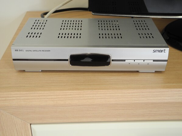Ein Satellitenempfänger auf einer Holzoberfläche, im Hintergrund ein Laptop.