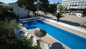 Una piscina con sillas de descanso y una palmera.