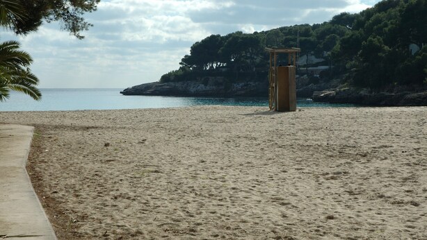 Una playa con una torre de salvavidas y un paseo marítimo de hormigón.