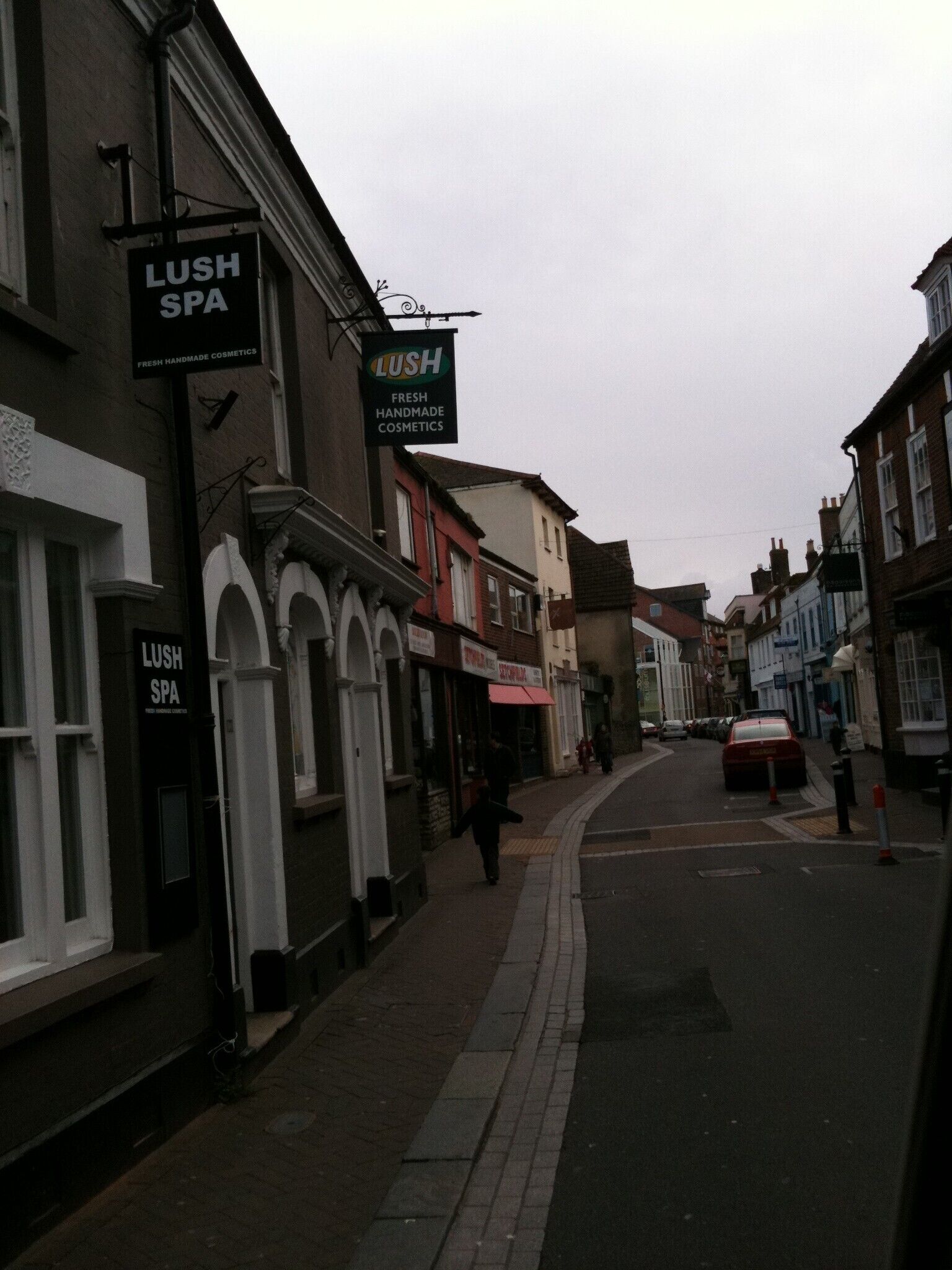 Une rue bordée d’immeubles, dont un spa LUSH et un magasin LUSH vendant des produits de beauté artisanaux et frais.