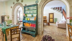 A cozy living room with a green bookshelf, a dining table with chairs, a staircase, and a sofa. - WELCOME, TRADITION, NATURE WITH POOL (Fermo)