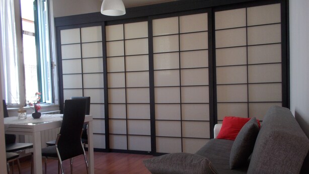 A living room with a sofa, a dining table with chairs, and a shoji screen wall. - The attic of Val. Apartment with large terrace, in a period cottage. (Roma)
