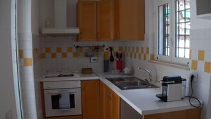 A compact kitchen with wooden cabinets, a white countertop, a built-in oven, a sink, and a window with a view. - The attic of Val. Apartment with large terrace, in a period cottage. (Roma)