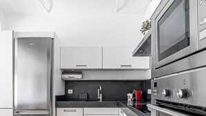 Una cocina moderna con electrodomésticos de acero inoxidable, una mesa de comedor de madera y un suelo con diseño de espiga.