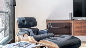 Una sala de estar moderna con un sillón de cuero reclinable, una mesa de centro de madera, un televisor y una estantería.