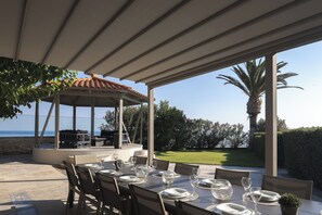 An outdoor dining area with a covered patio, a gazebo, and a view of the sea.