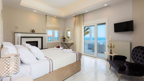 Een moderne slaapkamer met een groot bed, een open haard, een balkon met uitzicht en een flatscreen televisie.