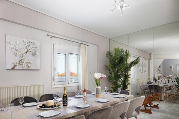 A modern dining area with a long table, chairs, and a large potted plant.