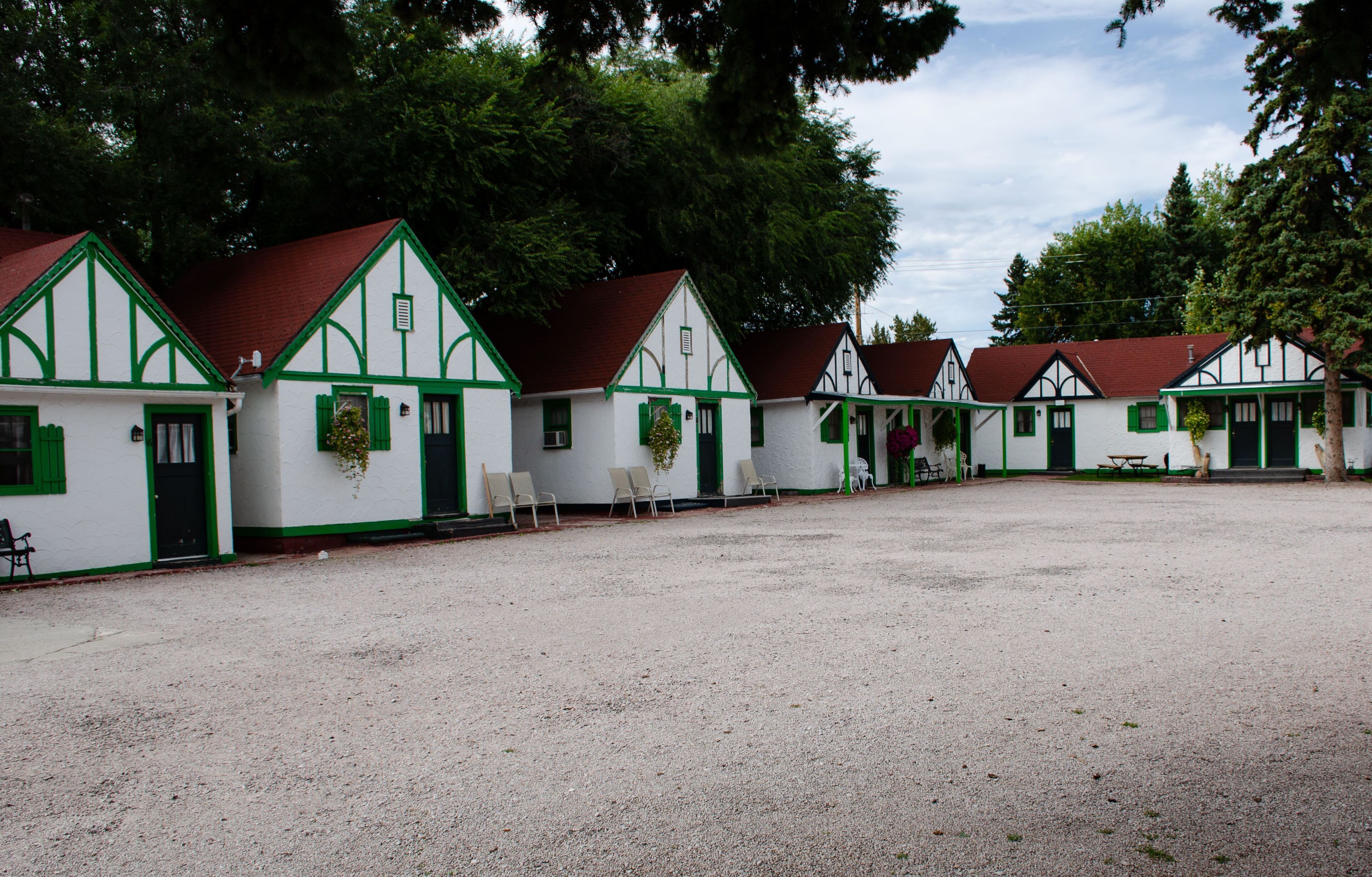A row of traditional half-timbered houses with green shutters and a gravel courtyard.