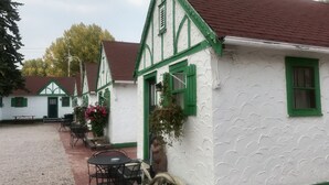 Eine Reihe traditioneller weißer Gebäude mit grünen Akzenten und rotem Dach, mit Außenbestuhlung und einem Kiesweg.