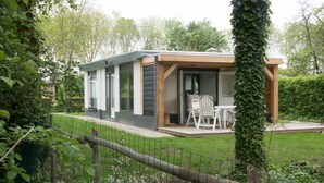 Ein modernes Haus mit Terrasse, inklusive Tisch und Stühlen.