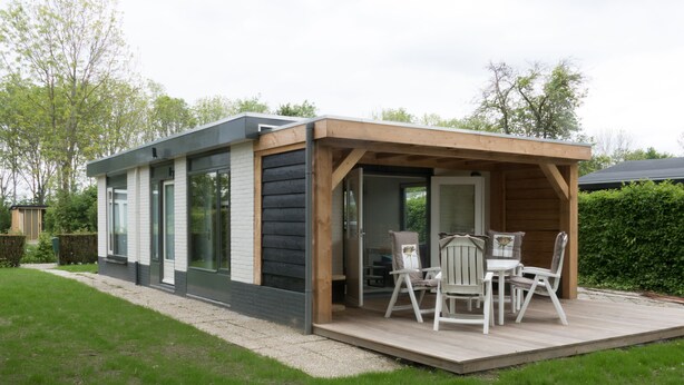Ein modernes Haus mit Terrasse und Gartenmöbeln.