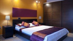 A modern bedroom with a large bed, two bedside tables, and a wardrobe.