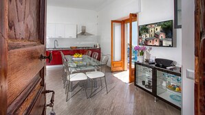 Una cocina moderna con armarios blancos, encimera roja y mesa de comedor de cristal.