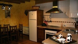 Una cucina con frigorifero, fornello, lavello e sedie di legno.